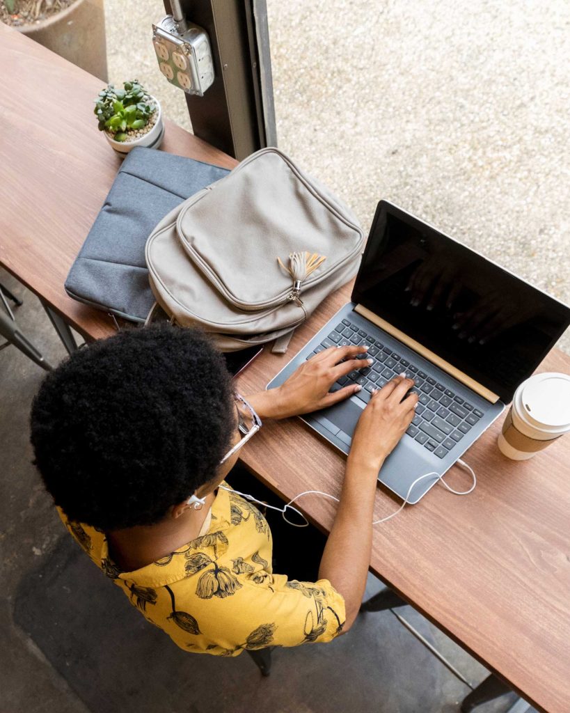 woman working at a wooden desk on a laptop from a birds eye view